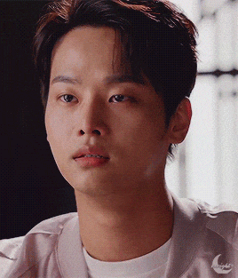 a close up of a young man 's face with a crescent moon on his jacket