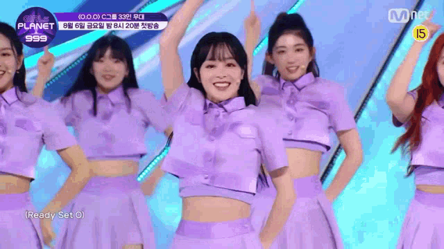a group of girls are dancing on a stage in purple outfits .