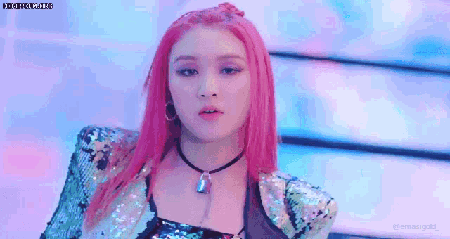 a woman with pink hair and a necklace is wearing a sequined jacket .