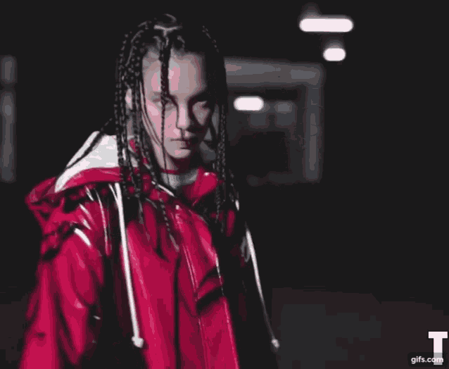 a woman with braids wearing a red jacket with the letter t on it