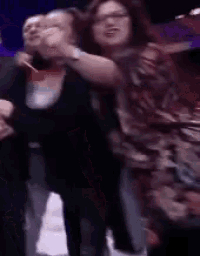 a group of people are standing next to each other and dancing in a dark room .