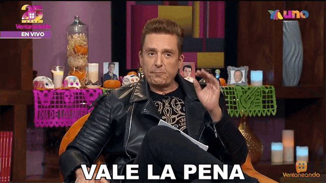 a man in a leather jacket says vale la pena on a screen
