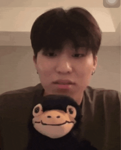 a young man is holding a stuffed monkey in his hands .
