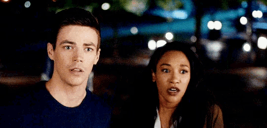 a man and a woman are standing next to each other with their mouths open and their hands in the air .