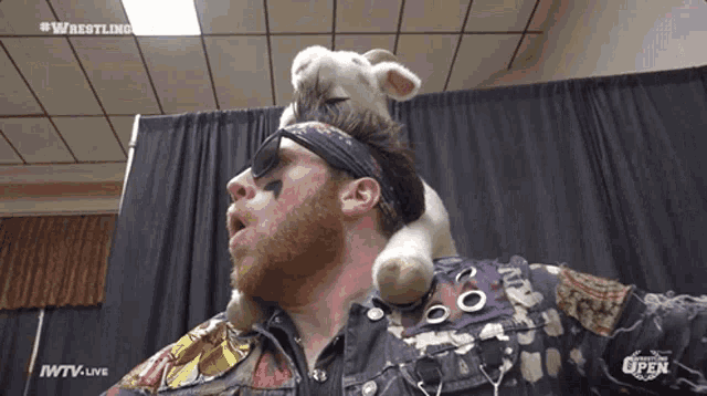 a man is holding a stuffed animal on his head with iwtv live in the corner
