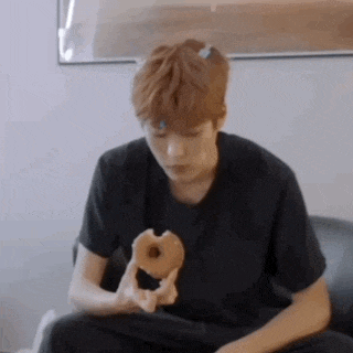 a man is sitting on a couch eating a donut .