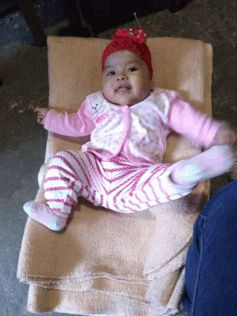 a baby is laying on a blanket wearing a pink outfit that says ' minnie ' on it