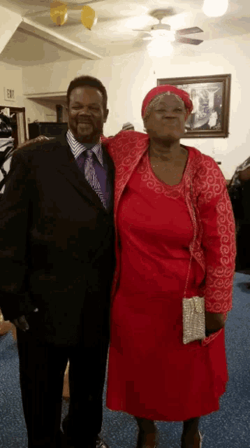 a man in a suit and a woman in a red dress posing for a picture