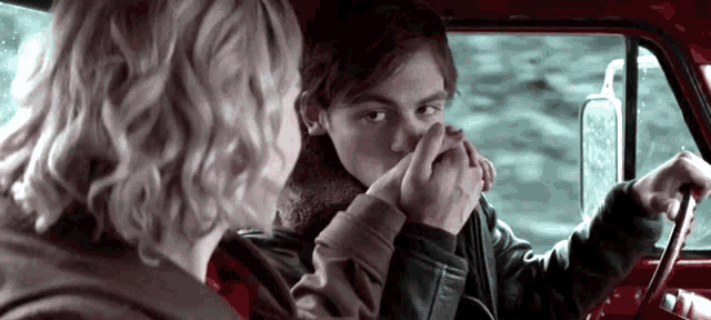 a man holds a woman 's hand while driving a red truck
