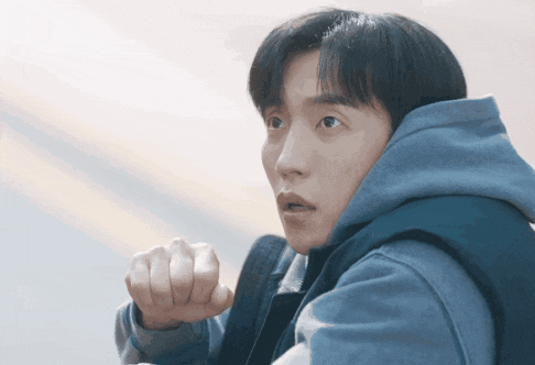 a man wearing a blue hoodie holds his fist up in the air