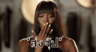 a woman is blowing a kiss with her hand over her mouth in a foreign language .