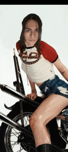 a woman is sitting on a motorcycle wearing a red and white t-shirt that says ' s. james '