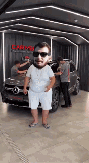 a man wearing sunglasses and flip flops is standing in front of a car .