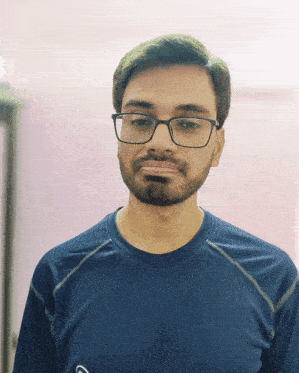 a man with glasses and a beard is wearing a blue shirt with the letter g on it