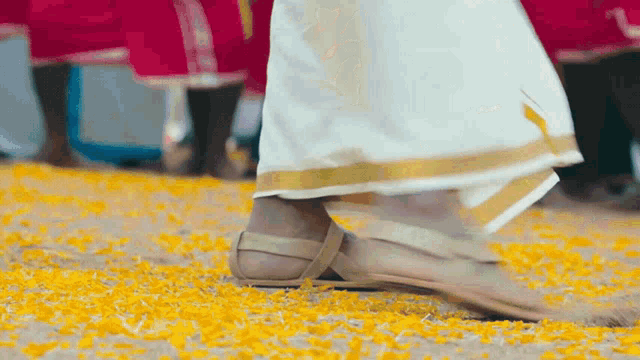 a person 's feet are standing on a pile of yellow petals on the ground