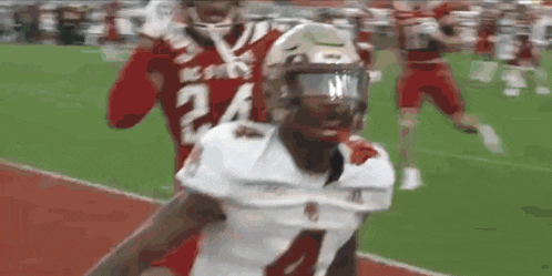 a football player with the number 24 on his jersey is being tackled by another player on a field .