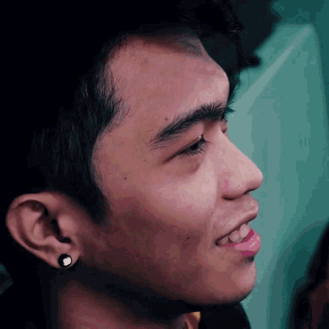 a close up of a young man 's face with a piercing in his ear
