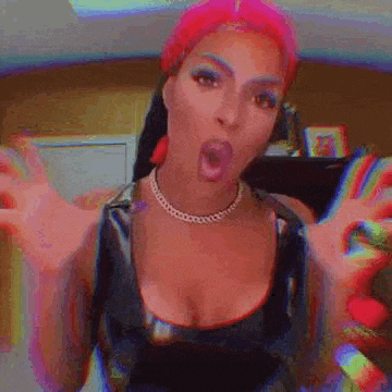 a woman with pink hair and a necklace is making a funny face with her arms outstretched .