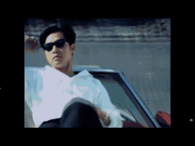 a man wearing sunglasses sits in a car
