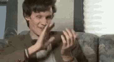 a man in a suit is sitting on a couch making a funny face .