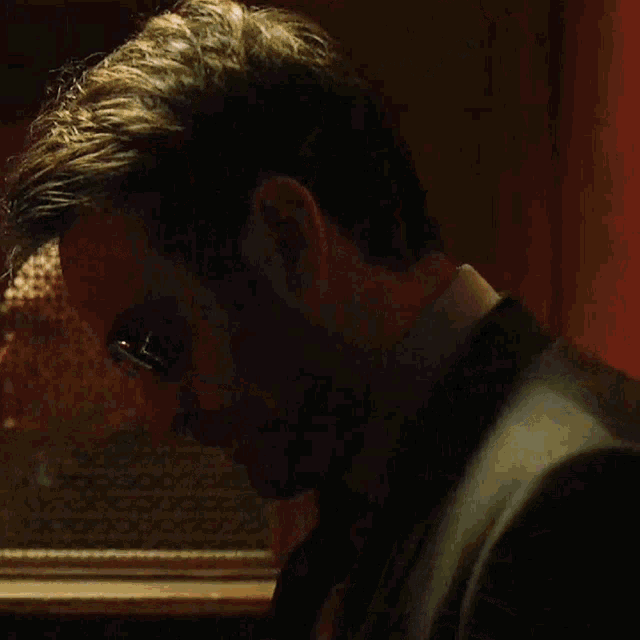 a man in a suit adjusts his tie in front of a mirror