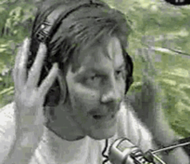 a man is wearing headphones and talking into a microphone in a black and white photo .