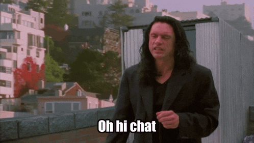 a man with long hair says oh hi chat in front of a city