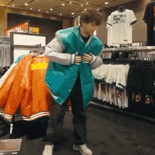 a man is trying on a miami dolphins jacket in a clothing store
