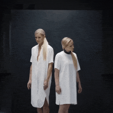 two women standing next to each other in white dresses