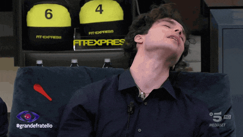 a man laying on a couch with his eyes closed in front of a sign that says fit express