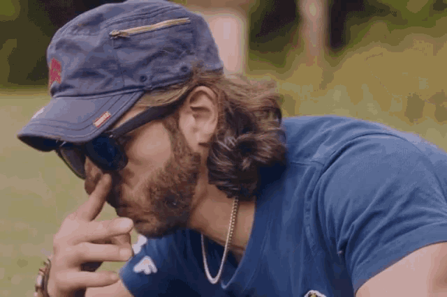 a man with a beard wearing a blue shirt and a hat