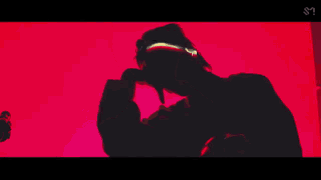 a close up of a person holding a pink object in a red room with neon lights .
