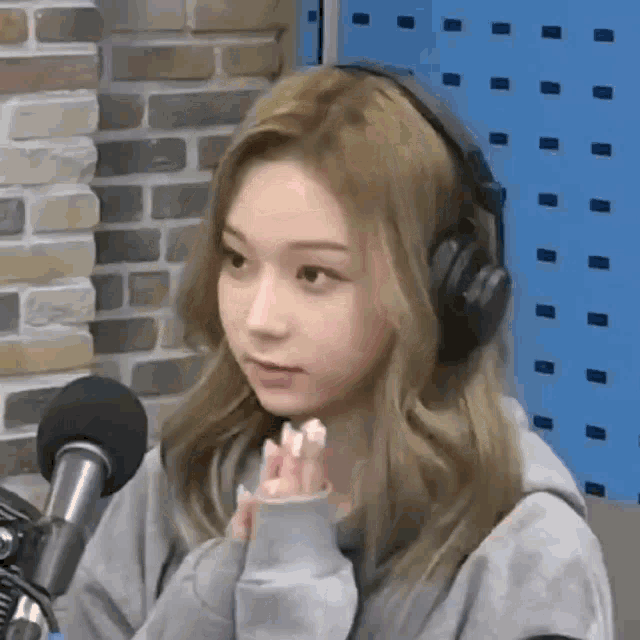 a woman wearing headphones is sitting in front of a microphone in a room .
