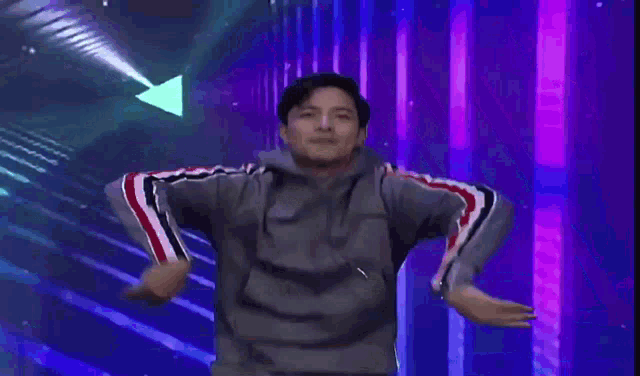 a young man in a grey jacket is dancing on a stage .