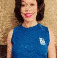 a woman wearing a blue shirt with a logo on the front smiles for the camera
