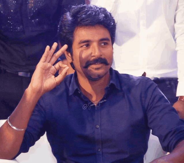 a man with a mustache wearing a blue shirt has a watermark on his shirt that says ' smit rajan '