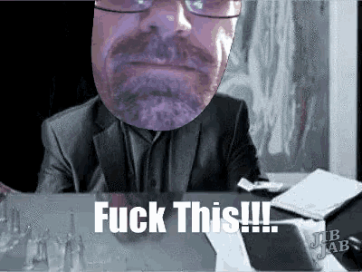 a man with glasses and a beard is sitting at a desk and says fuck this