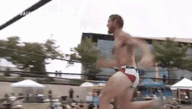a man without a shirt is jumping in the air in a boxing ring .