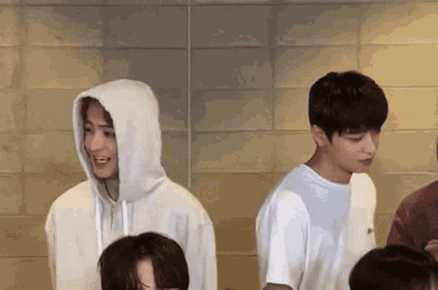 a group of young men are standing next to each other in front of a brick wall .