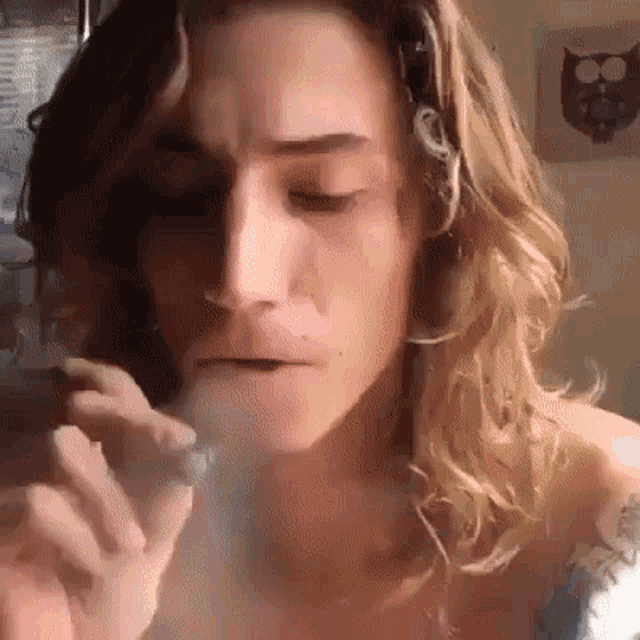 a man with long hair is smoking a cigarette in front of an owl .