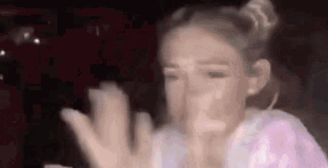 a woman is covering her face with her hands while sitting in a car .