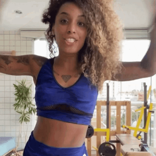 a woman with curly hair is wearing a blue top and shorts