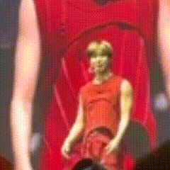 a man in a red tank top is standing in a red car .