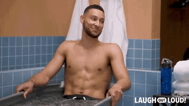 a shirtless man is sitting in a bathtub with the words laugh out loud behind him