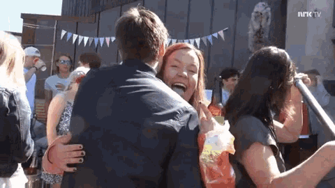 a group of people are hugging and laughing in front of a building that says nrk tv