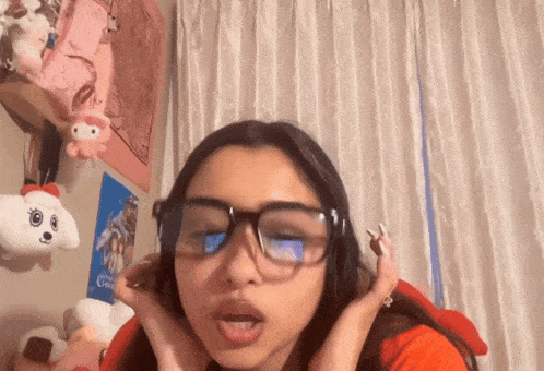 a girl wearing glasses with a hello kitty stuffed animal hanging on the wall