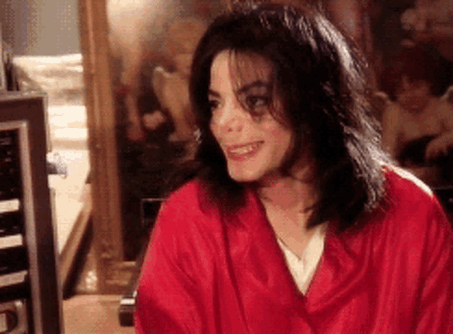 a man wearing a red robe is smiling in front of a mirror