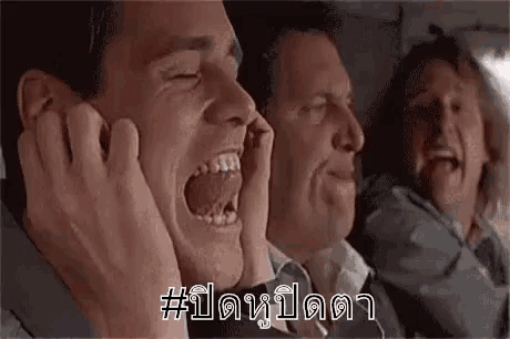 a group of men are screaming and covering their ears with their hands while sitting on a plane .