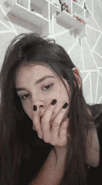 a girl with black nails is covering her face with her hand