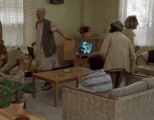 a group of people are gathered in a living room watching television